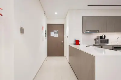 a kitchen with white counters and a brown door at Grande Residence, Downtown - 1 Bedroom Apartment - Allsopp & Allsopp in Dubai
