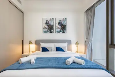 a bedroom with a large white bed with blue sheets at Grande Residence, Downtown - 1 Bedroom Apartment - Allsopp & Allsopp in Dubai