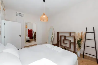 a white bedroom with a bed and a mirror at Al Dhafrah 4, The Greens - Onelink in Dubai