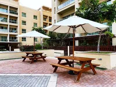 two picnic tables and an umbrella in a courtyard at Al Dhafrah 4, The Greens - Onelink in Dubai