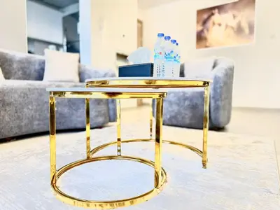 a gold side table in front of a couch at Majestic 2 BHK Park view at Liwan 2- Dubai in Dubai