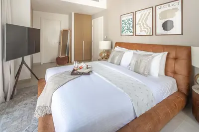 a bedroom with a large bed and a flat screen tv at Frank Porter - Grove at Creek Beach Building in Dubai