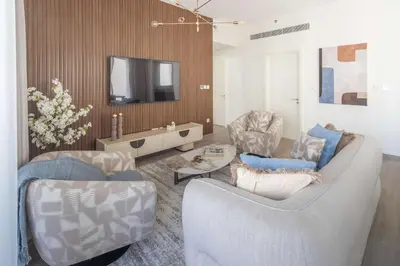 a living room with two chairs and a tv at Frank Porter - Grove at Creek Beach Building in Dubai