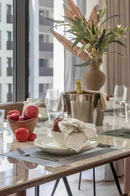 a dining room table with plates and glasses and a plant at Frank Porter - Grove at Creek Beach Building in Dubai