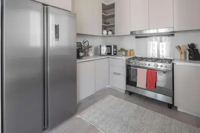 a kitchen with white cabinets and a stainless steel refrigerator at Frank Porter - Grove at Creek Beach Building in Dubai