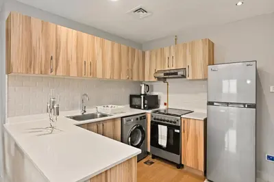 a kitchen with wooden cabinets and a stainless steel refrigerator at Modern Luxury 2BR Apartment In Dubai Sports City in Dubai