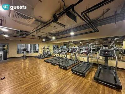 a gym with rows of treadmills in a room at HiGuests - Experience Luxury 1BR Living at Autumn-1A in JVC in Dubai
