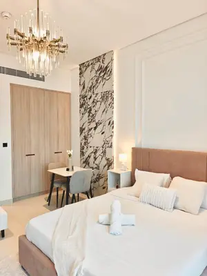 a bedroom with a large white bed and a table at Stylish New Studio Apartment with Balcony in Dubai