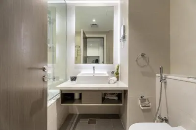 a white bathroom with a sink and a mirror at GuestReady - Studio l Canal Views | Business Bay in Dubai