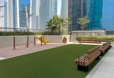 a park with benches and artificial grass and tall buildings at GuestReady - 1BR l Canal View | Business Bay in Dubai