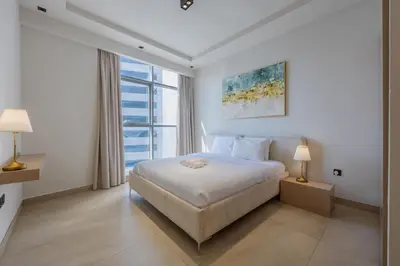 a white bedroom with a bed and a large window at Skyview Luxe 4BR - Elegant Sea & Ain Dubai View in Dubai