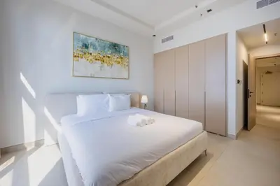 a white bedroom with a white bed and a painting at Skyview Luxe 4BR - Elegant Sea & Ain Dubai View in Dubai