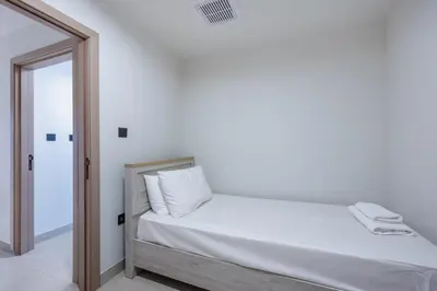 a white bedroom with a bed and a mirror at Skyview Luxe 4BR - Elegant Sea & Ain Dubai View in Dubai