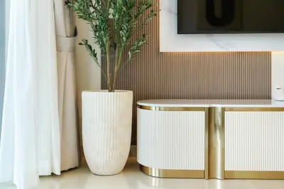 a white vase with a plant in it next to two tables at Classy and Chic 2BR in Downtown with Burj Khalifa View in Dubai