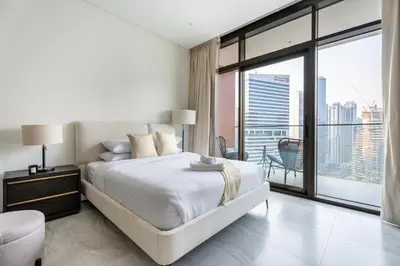 a white bedroom with a large bed and a balcony at GuestReady - Studio | Canal View & Burj Khalifa in Dubai