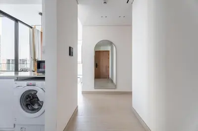 a hallway with a washer and dryer in a white apartment at GuestReady - Luxury with a Private Pool | 2 BHK in Dubai