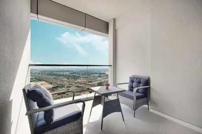 a room with two chairs and a table and a large window at Cozy 2BR Aykon City Near Downtown - Pool and Gym in Dubai