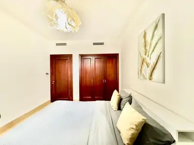 a white room with a bed and wooden doors at Downtown close to Dubai mall in Dubai