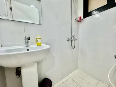 a white bathroom with a sink and a shower at Al Khaleej Apartments Karama in Dubai