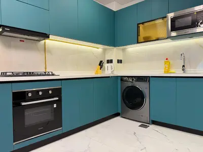 a kitchen with blue cabinets and a washer and dryer at Studio and One bedroom in Danube Opalz by The S Holiday Homes in Dubai