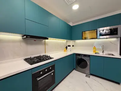 a kitchen with blue cabinets and a washing machine at Studio and One bedroom in Danube Opalz by The S Holiday Homes in Dubai