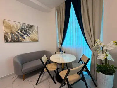 a living room with a table and chairs and a couch at Studio and One bedroom in Danube Opalz by The S Holiday Homes in Dubai