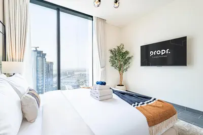 a bedroom with a white bed with a large window at Sobha Crest Luxury Apartments in Dubai
