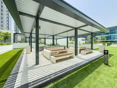 a pavilion with benches and tables on a lawn at Sobha Crest Luxury Apartments in Dubai
