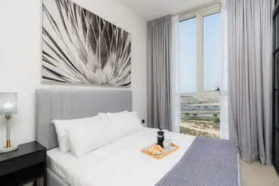 a bedroom with a white bed and a large window at Modern Amenities - Great Community in Dubai