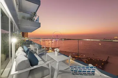 a balcony with a view of the water at sunset at La Brisa Exclusive 3BHK at 1JBR Sea Palm Royal Atlantis Burj AlArab View with Private Beach and Pool By La Brisa Dubai in Dubai