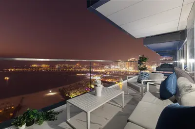 a balcony with a view of a city at night at La Brisa Exclusive 3BHK at 1JBR Sea Palm Royal Atlantis Burj AlArab View with Private Beach and Pool By La Brisa Dubai in Dubai
