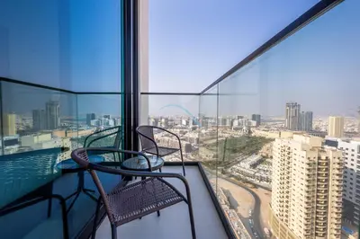 a balcony with two chairs and a view of a city at Modern Studio on High Floor with Stunning City Views near Circle Mall and Community Parks - Binghatti Tulip, JVC - by Deluxe Holiday Homes in Dubai