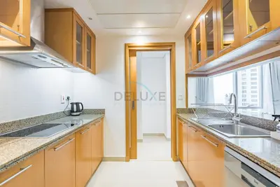 a kitchen with wooden cabinets and a large window at Next to Marina Canal 1BR, Easily Accessible from the Tram, a Short Stroll to Marina Beach and The Walk, Beauport X1, Dubai Marina - by Deluxe Holiday Homes in Dubai