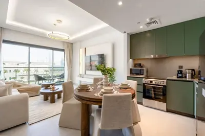 a kitchen and living room with green cabinets and a table at Elegant 1 Bedroom with Balcony in City Walk in Dubai
