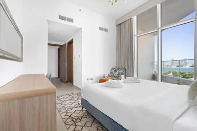a bedroom with a large bed and a large window at VayK - Luxurious 2BR on the Palm with Private Beach Access in Dubai