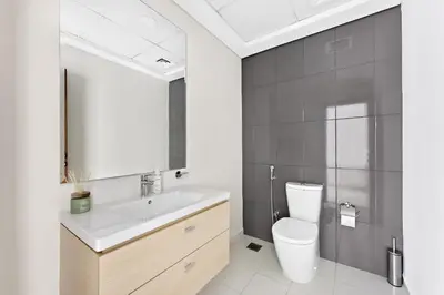 a bathroom with a sink and a toilet and a mirror at VayK - Great 1BR Apartment in Damac Hills in Dubai