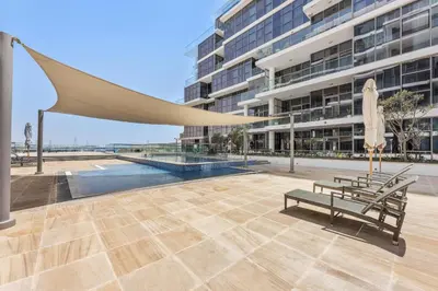 a bench and umbrella in front of a building at VayK - Great 1BR Apartment in Damac Hills in Dubai