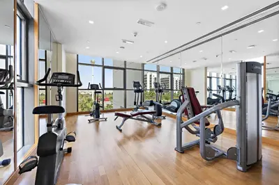 a gym with several treadmills and elliptical machines at VayK - Great 1BR Apartment in Damac Hills in Dubai