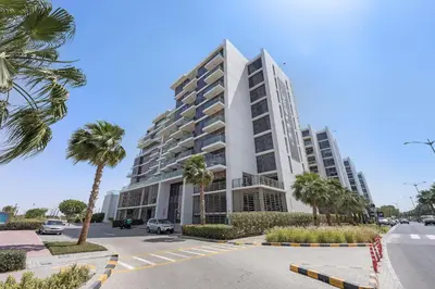 a large white building with palm trees in a parking lot at VayK - Great 1BR Apartment in Damac Hills in Dubai