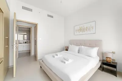 a white bedroom with a large bed and a bathroom at VayK - Stylish 1BR in Iconic Downtown Location in Dubai