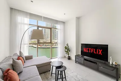 a living room with a couch and a tv at Vayk - Bright and Spacious 2BR with Panoramic Marina Views in Dubai