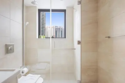 a bathroom with a shower with a toilet and a window at Vayk - Bright and Spacious 2BR with Panoramic Marina Views in Dubai