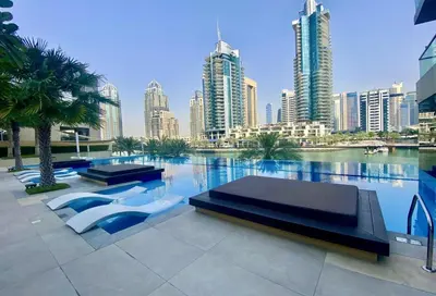 a pool with two beds and a city skyline at Vayk - Bright and Spacious 2BR with Panoramic Marina Views in Dubai