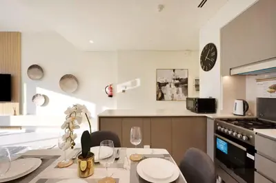 a kitchen with a table and a clock on the wall at Luxury Grande Signature Apartment in Dubai Downtown Steps to Dubai Mall and Burj Khalifa with Stunning Pool View by La Brisa Dubai in Dubai