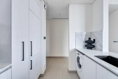 a white kitchen with white cabinets and a dishwasher at GuestReady - High floor Luxury with a Private Pool in Dubai