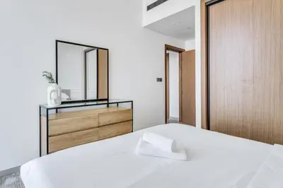 a bedroom with a white bed and a mirror at GuestReady - High floor Luxury with a Private Pool in Dubai