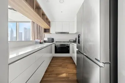 a kitchen with white cabinets and a wooden floor at Luxury 2BR Walk-In Closet Full Burj Khalifa View in Dubai