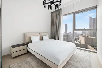 a white bedroom with a bed and a window at Luxury 2BR Walk-In Closet Full Burj Khalifa View in Dubai