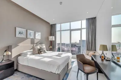 a hotel room with a bed and a desk and a window at GuestReady - Damac Prive | 1BR Canal View in Dubai