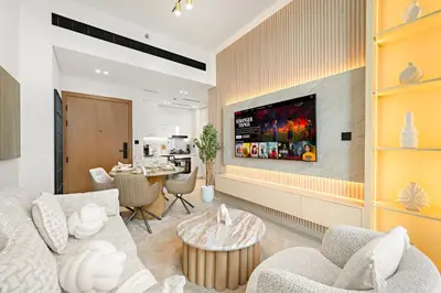 a living room with a tv on a wall at Cozy 1 Bedroom in JVC with Stunning City Views in Dubai